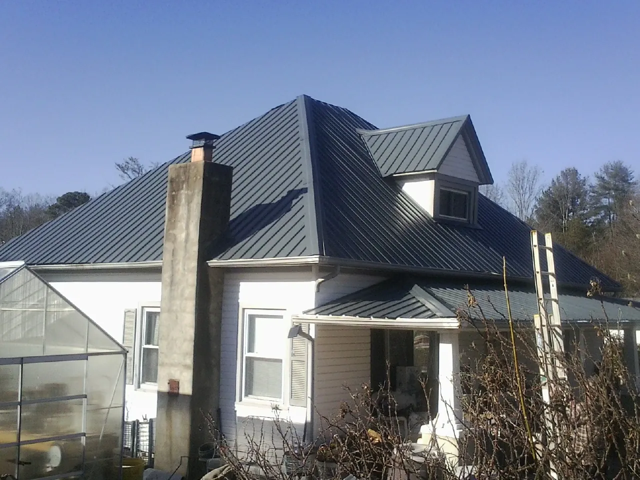 Dark blue standing seam metal roof on a white farmhouse with dormer — Slate & Tile Roof Repair by Roofing Brothers in Fidelity
