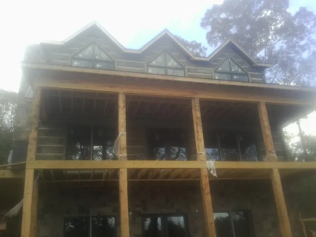 Dormers and porch framing on a large log home under construction — Roof Coating work by our crew in Fidelity