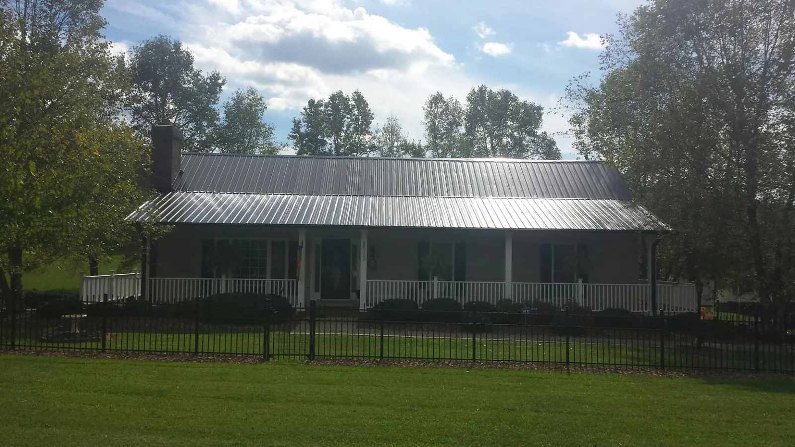 Gray metal roof on a brick ranch with a full width front porch — Gutter Guard Installation work by our crew in Fidelity