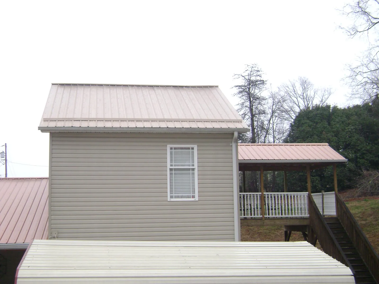 Tan metal roofs on a two story addition and attached porch, from a Roof Replacement job in Fidelity