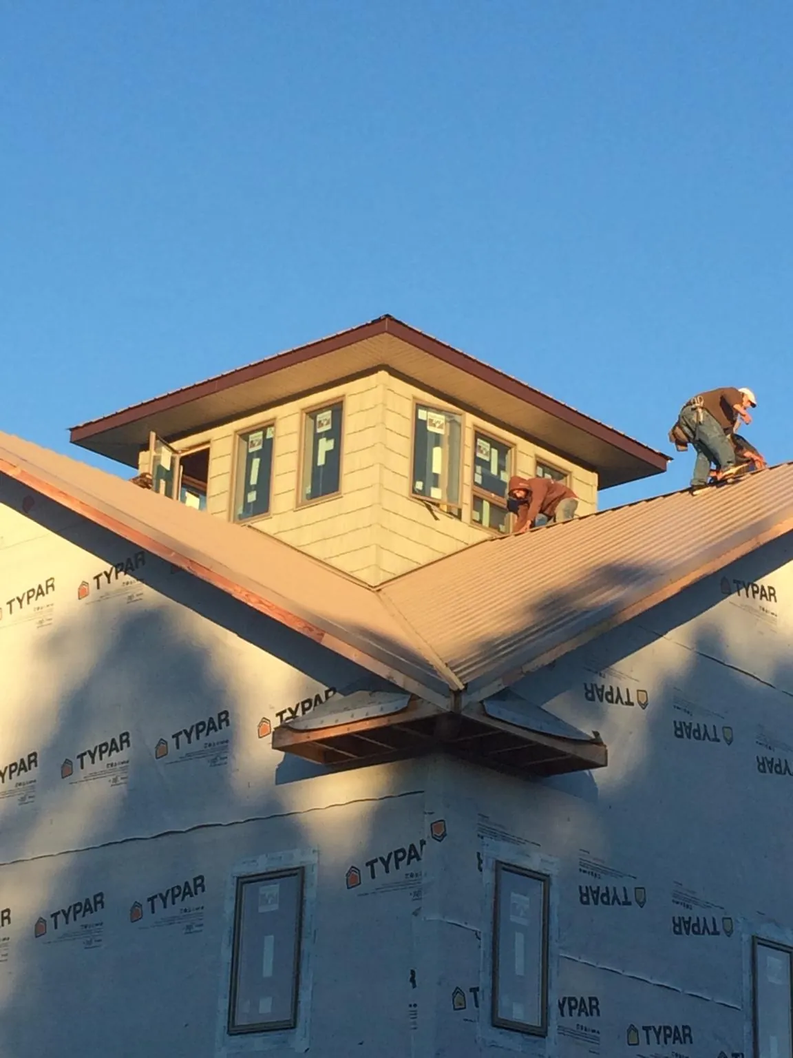 Roofers working around a rooftop cupola on a new metal roof at sunset — Roof Waterproofing in Fidelity by Roofing Brothers